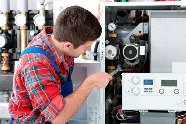 HVAC technician inspecting and repairing boiler controls in Parker