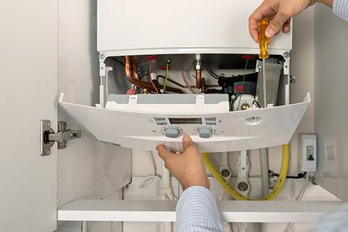 HVAC technician repairing an indoor boiler in Parker